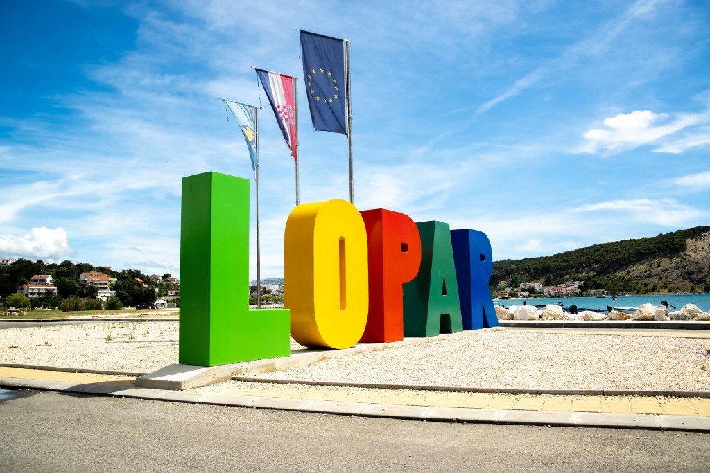 Buntes LOPAR-Willkommensschild am Hafen – Kroatien, EU und Regionalflagge